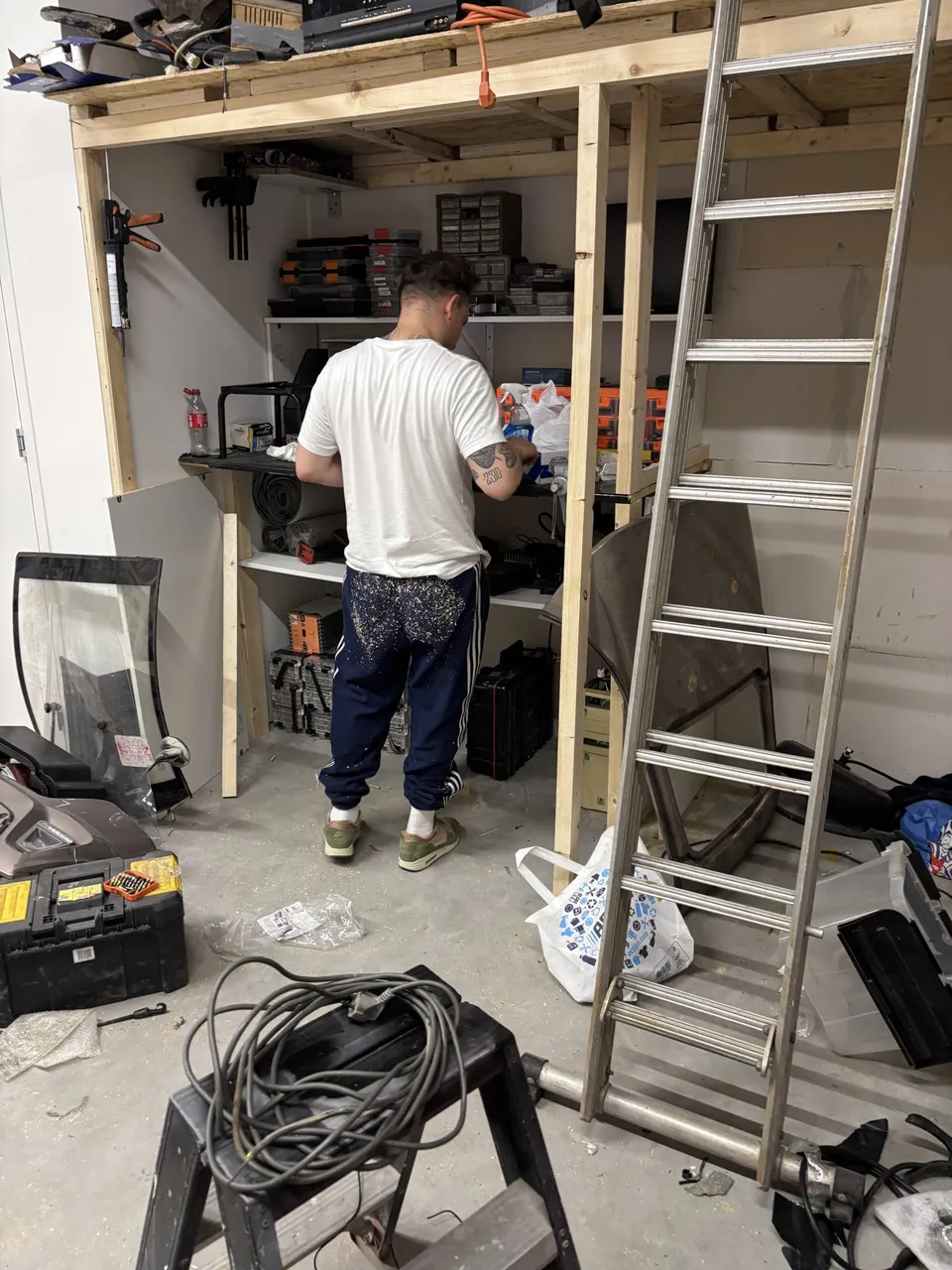 Leonidas in the Weesp workshop — sawdust on the pants, mid-build, racks going up around him
